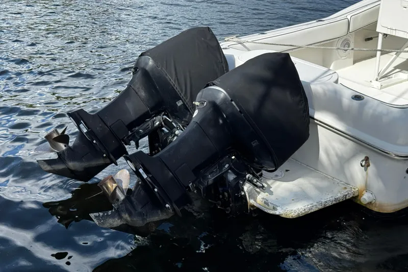Slide: The Image of Twin outboard motors on a 2004 Dusky 33 boat, partially covered, docked on water. - 52