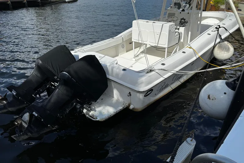 Slide: The Image of 2004 Dusky 33 boat with dual outboard motors docked on calm water. - 53