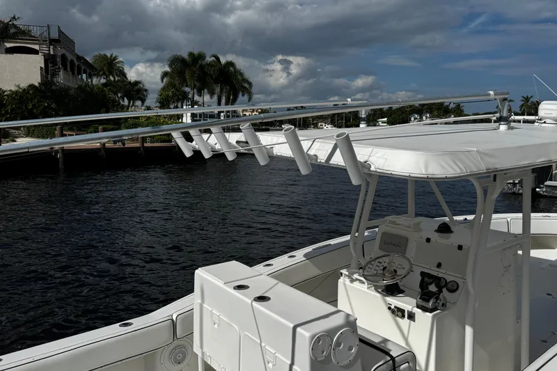 Slide: The Image of 2004 Dusky 33 boat docked by waterfront with palm trees and cloudy sky. - 55
