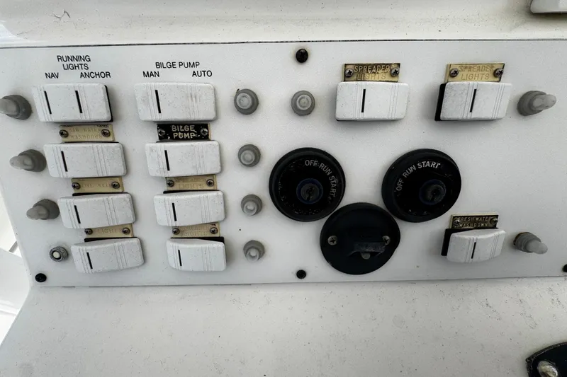 Slide: The Image of Control panel of a 2004 Dusky 33 boat with switches and dials. - 14