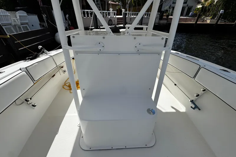 Slide: The Image of 2004 Dusky 33 boat interior with white seating and railing, docked by the water. - 27