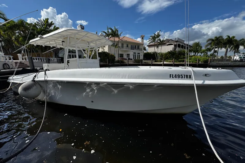 Slide: The Image of 2004 Dusky 33 boat docked by waterfront homes under a partly cloudy sky. - 3