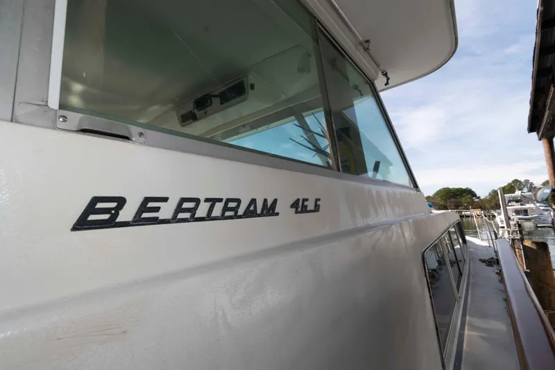 Slide: The Image of 1974 Bertram 46.6 yacht side view with logo, docked at marina. - 12