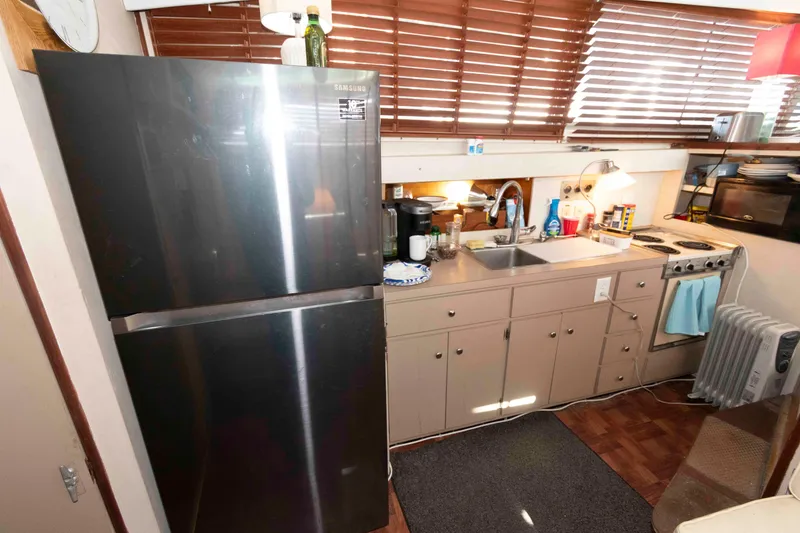 Slide: The Image of 1974 Bertram 46.6 yacht kitchen with modern appliances and wooden blinds. - 16