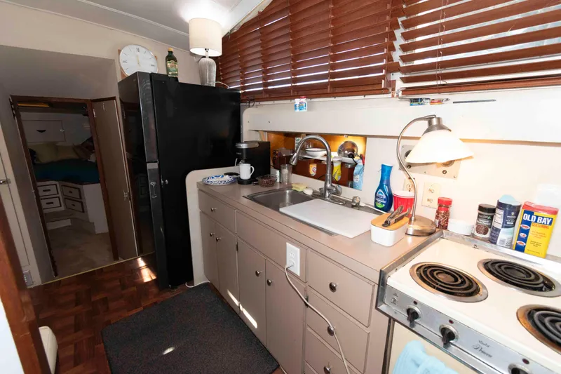 Slide: The Image of 1974 Bertram 46.6 yacht kitchen with stove, sink, and wooden blinds. - 17