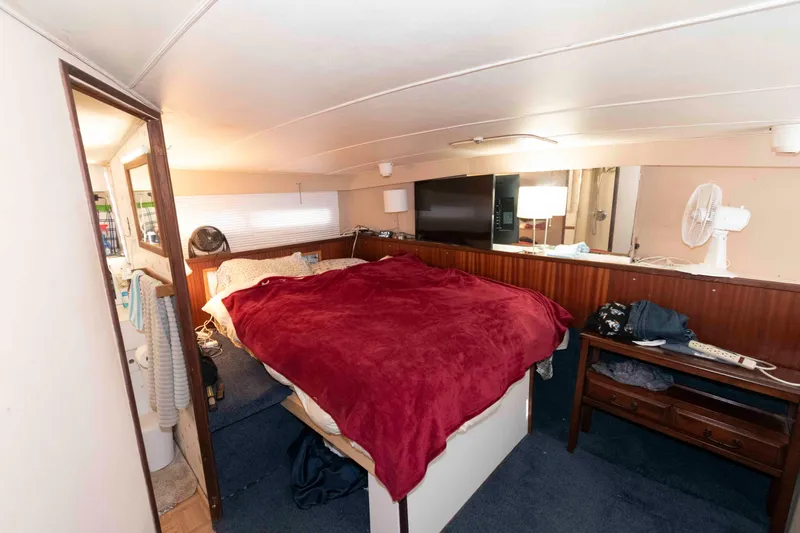 Slide: The Image of Cozy bedroom interior of a 1974 Bertram 46.6 yacht with red bedding and wooden accents. - 19