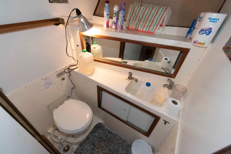 Slide: The Image of 1974 Bertram 46.6 yacht bathroom with sink, mirror, and toiletries. - 23