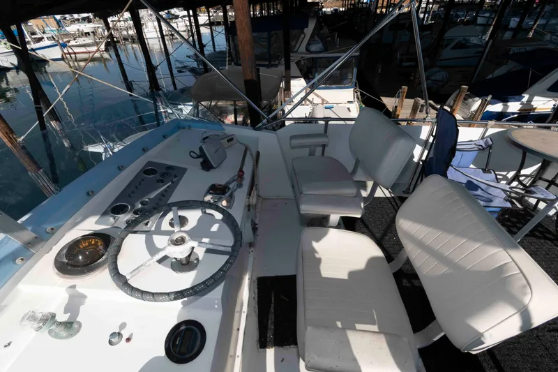 Slide: The Image of 1974 Bertram 46.6 yacht cockpit with steering wheel and white seating in marina. - 7