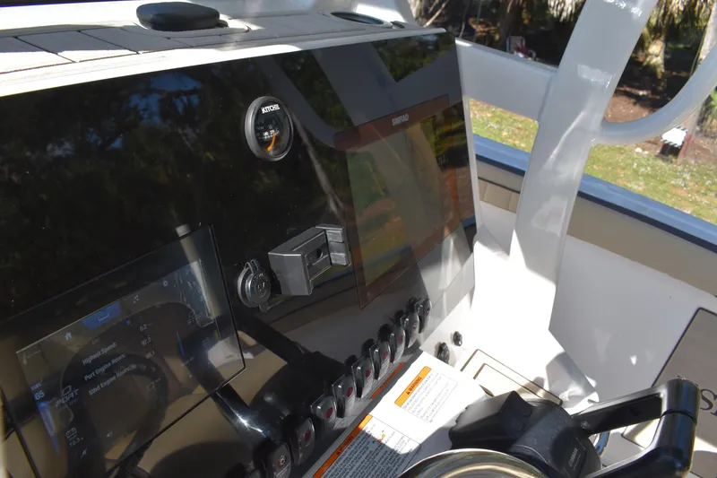 Slide: The Image of 2023 Yamaha Boats 252 FSH Sport interior with steering console and seating, displayed outdoors. - 15