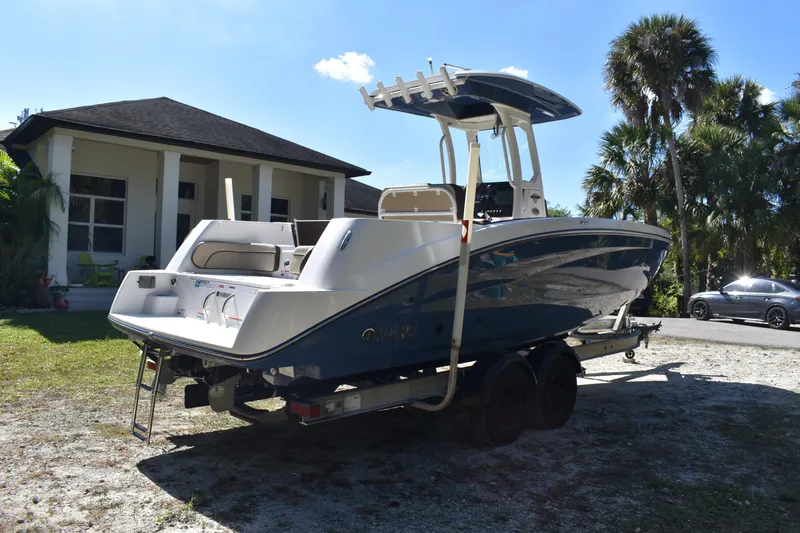 Slide: The Image of 2023 Yamaha Boats 252 FSH Sport on trailer, side view under clear blue sky. - 2