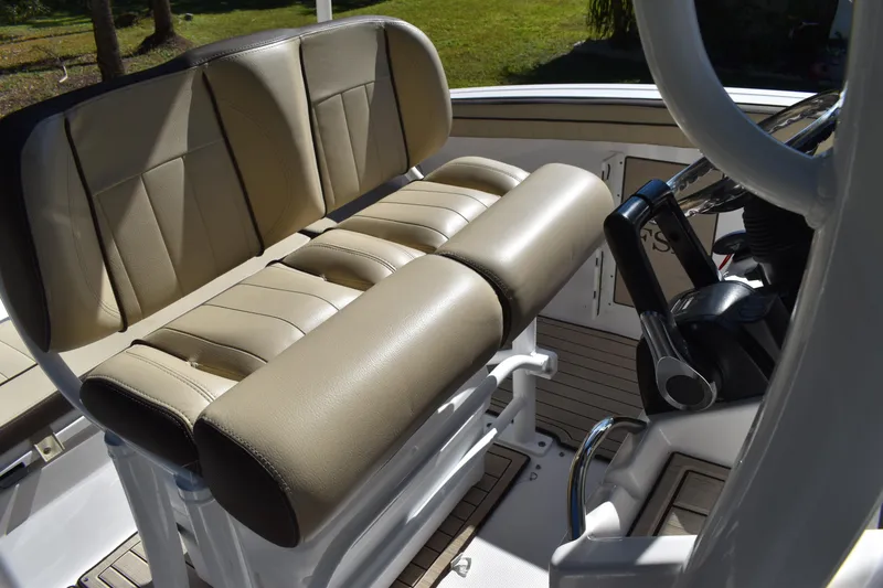 Slide: The Image of 2023 Yamaha Boats 252 FSH Sport interior, showcasing seating and storage, in a boatyard setting. - 29