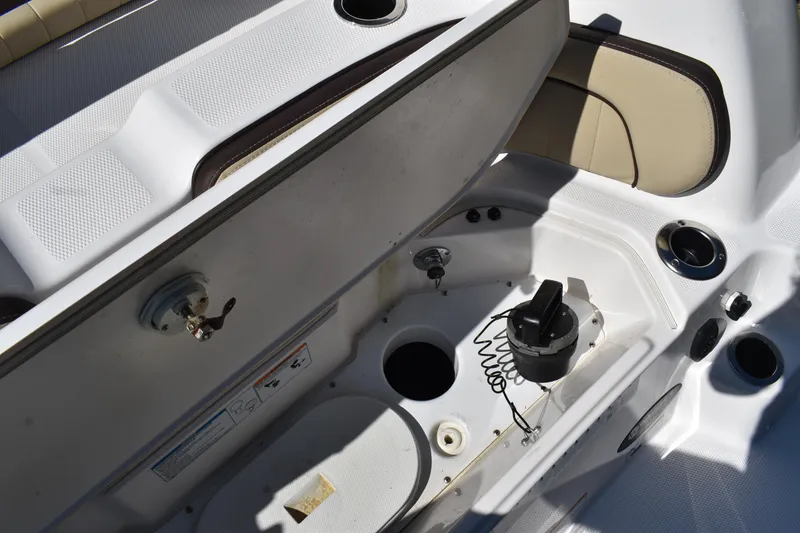Slide: The Image of 2023 Yamaha Boats 252 FSH Sport interior with seating and storage, docked outdoors. - 39
