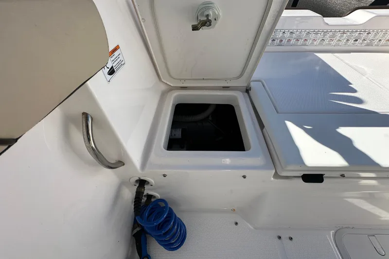 Slide: The Image of 2023 Yamaha Boats 252 FSH Sport storage compartment with open hatch and coiled hose. - 42
