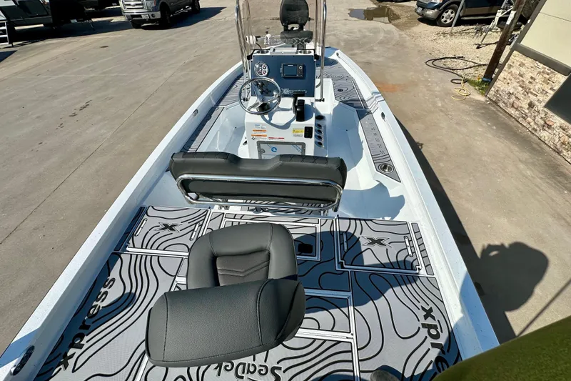 Slide: The Image of 2026 Express H20B boat interior with modern dashboard and seating, parked outdoors. - 11