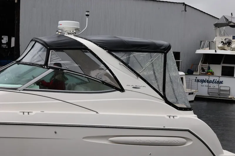 Slide: The Image of 2005 Maxum 3300 SE boat docked near a marina, featuring a black canopy. - 10