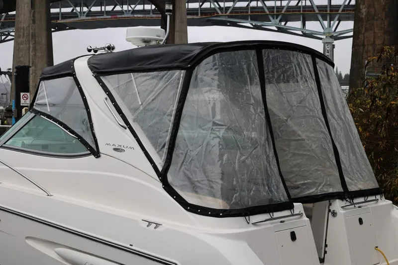 Slide: The Image of 2005 Maxum 3300 SE boat with clear canopy, docked near a bridge. - 13
