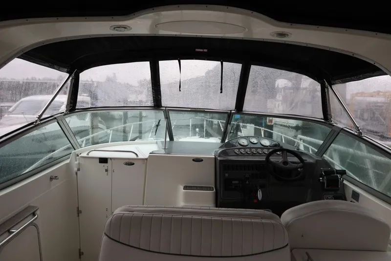 Slide: The Image of 2005 Maxum 3300 SE boat interior with steering wheel and dashboard in rainy weather. - 17