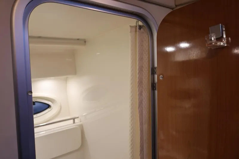 Slide: The Image of Interior view of 2005 Maxum 3300 SE boat cabin with wooden door and porthole. - 34