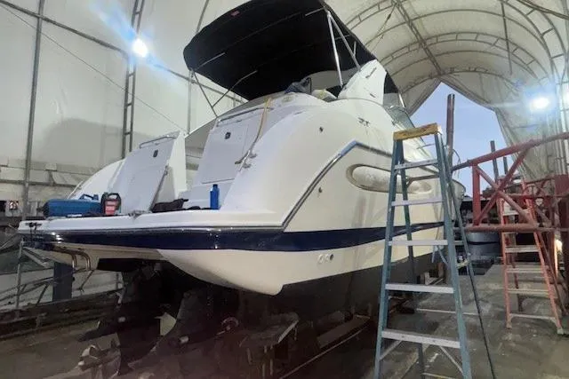 Slide: The Image of 2005 Maxum 3300 SE boat in a covered dock, undergoing maintenance with a ladder nearby. - 44