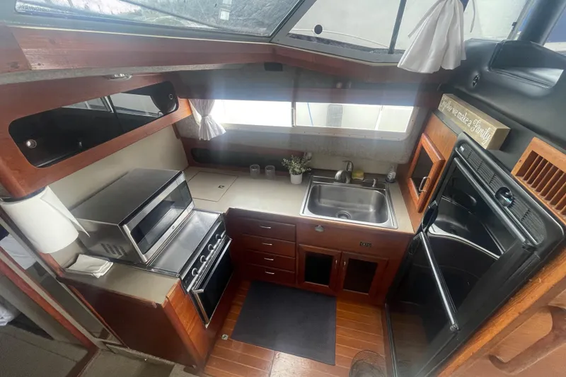 Slide: The Image of 1983 Bayliner 3888 MY Sedan kitchen with stove, sink, and wooden cabinetry. - 16