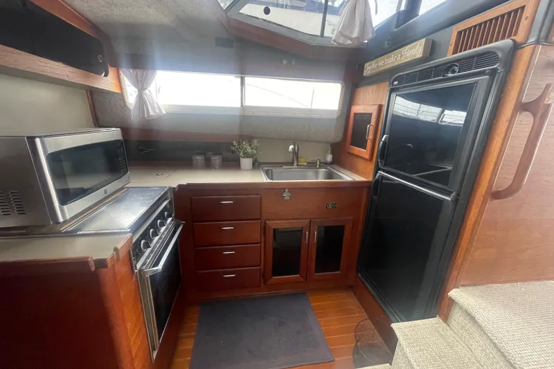 Slide: The Image of 1983 Bayliner 3888 MY Sedan kitchen with stove, microwave, sink, and refrigerator. - 17