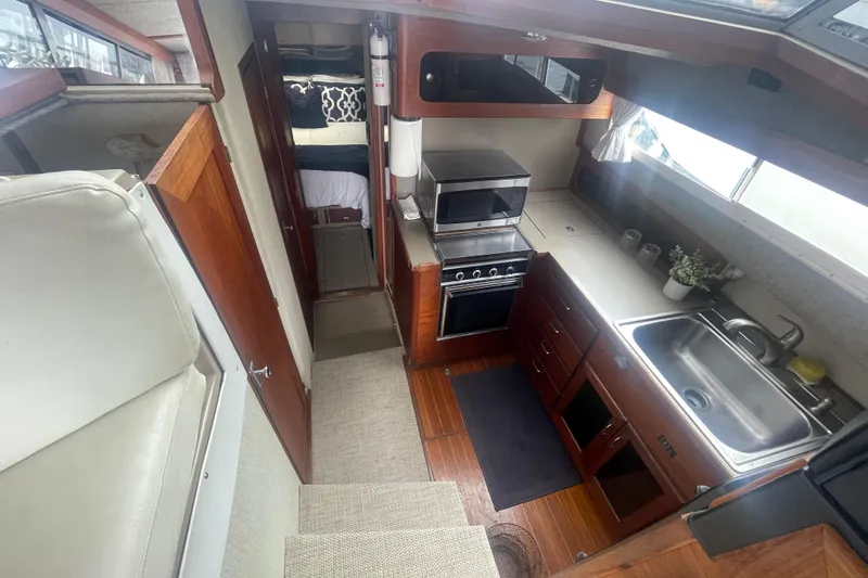 Slide: The Image of 1983 Bayliner 3888 MY Sedan interior with kitchen, stove, sink, and cozy sleeping area. - 18