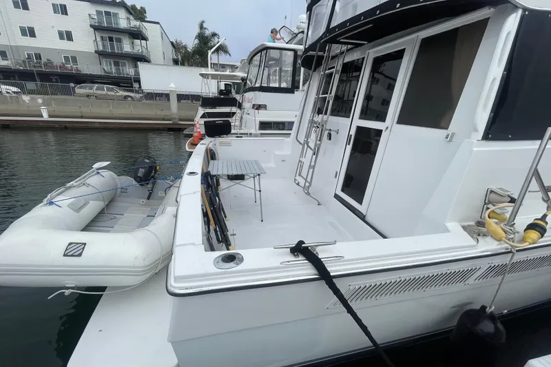 Slide: The Image of 1983 Bayliner 3888 MY Sedan docked with inflatable dinghy, marina background. - 3