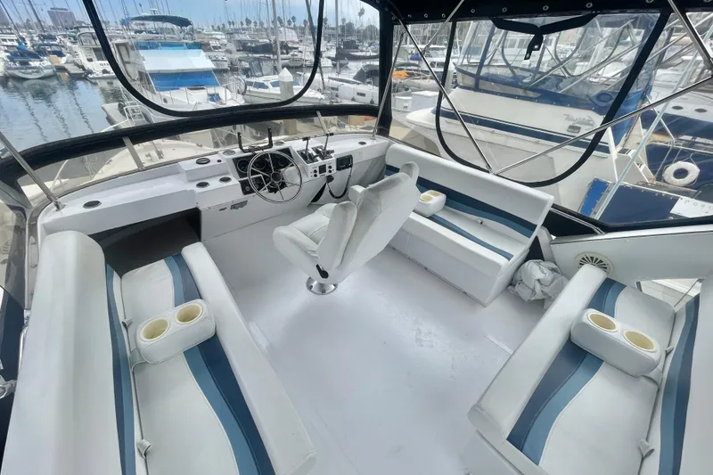 Slide: The Image of 1983 Bayliner 3888 MY Sedan interior with white seating, steering wheel, and marina view. - 7