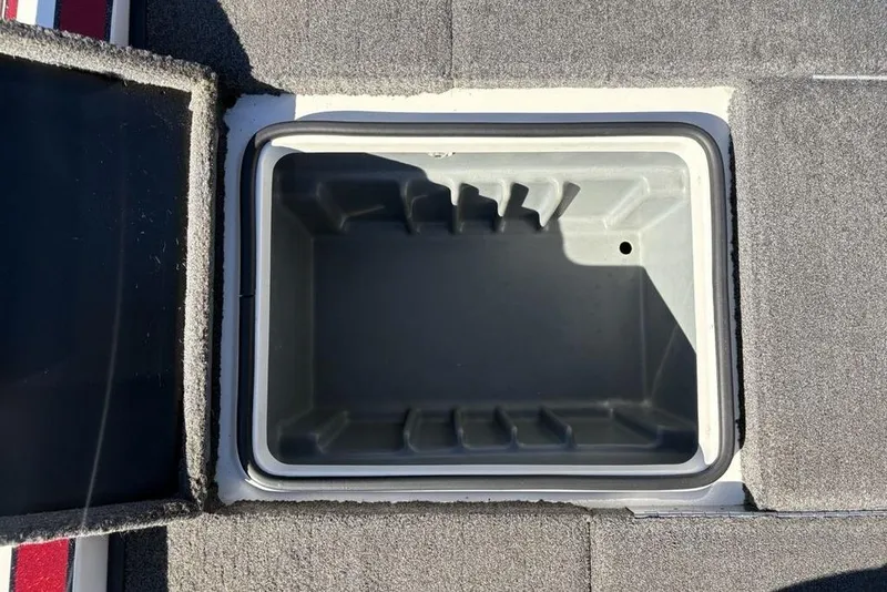 Slide: The Image of Open storage compartment in 2018 Triton 20 TrX Patriot boat, featuring gray interior and carpeted edges. - 32