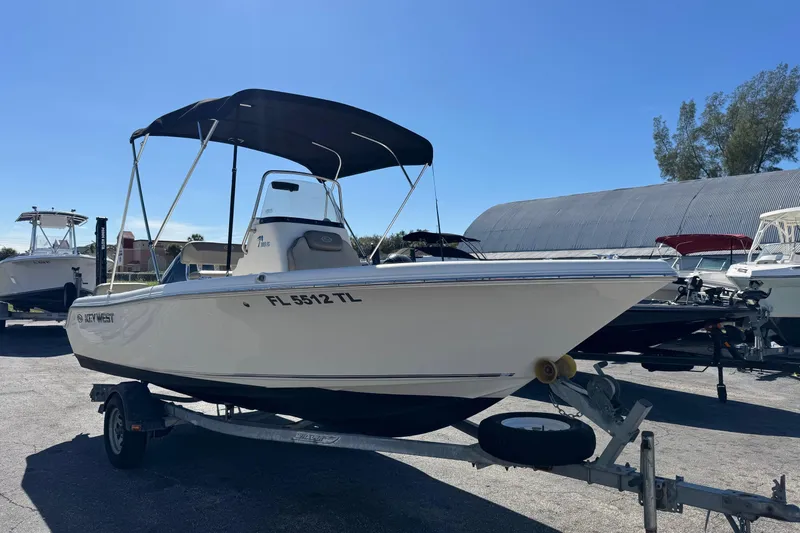 The Image of 2023 Key West 189 FS boat on trailer with canopy in sunny marina. - 0