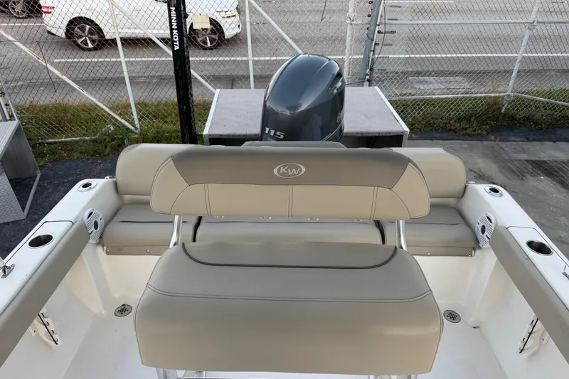 Slide: The Image of 2023 Key West 189 FS boat interior with seating and motor, parked near a fence. - 13