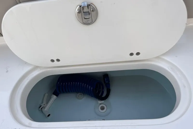 Slide: The Image of Open storage compartment on 2023 Key West 189 FS boat with coiled blue hose. - 21