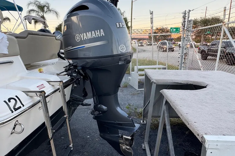 Slide: The Image of 2023 Key West 189 FS boat with Yamaha 115 outboard motor, parked near a fence. - 27