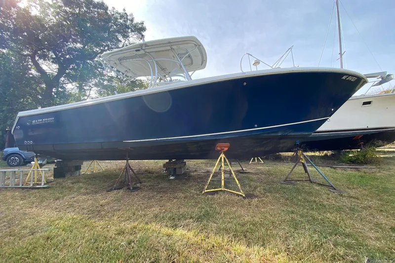 Slide: The Image of 2013 Sailfish 290 CC boat on stands, displayed outdoors. - 2