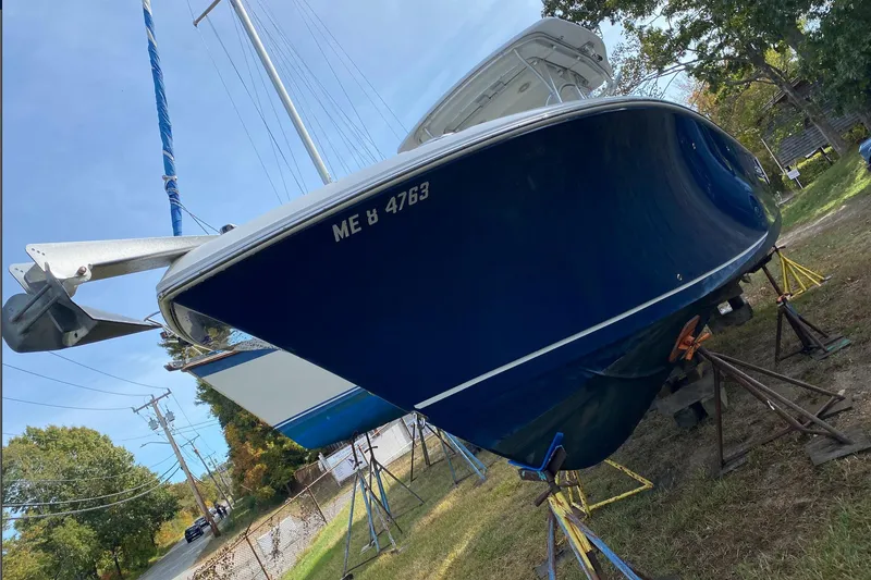 Slide: The Image of 2013 Sailfish 290 CC boat on stands, blue hull, outdoor setting. - 3