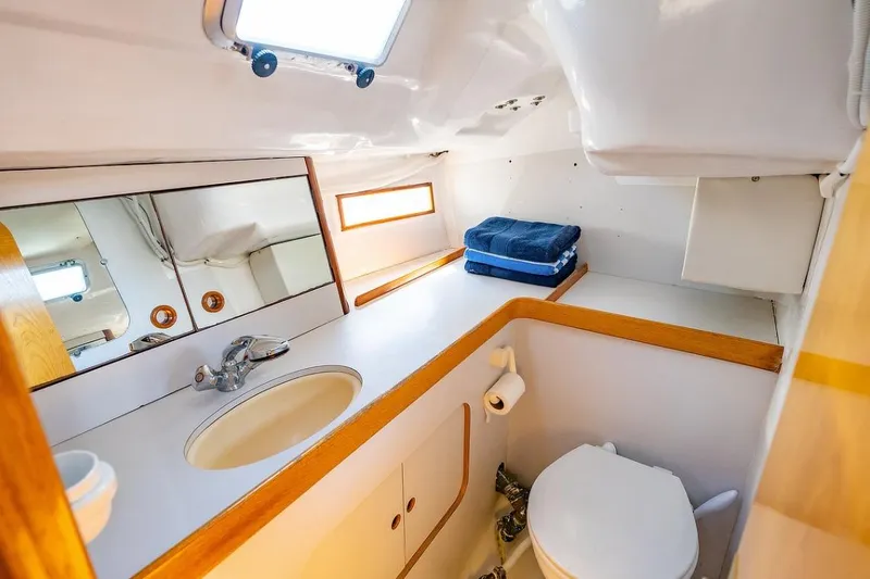 Slide: The Image of Interior of 1992 Beneteau Oceanis 350 sailboat, featuring wooden cabinetry and compact bathroom. - 6