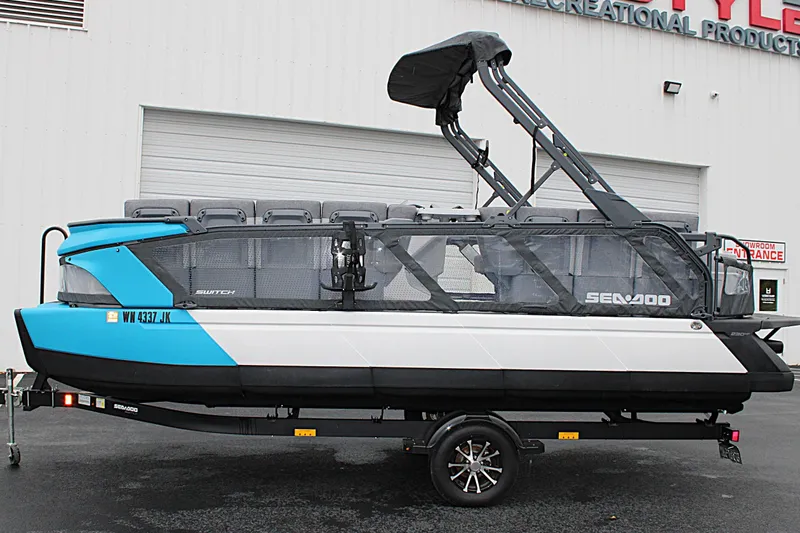 Slide: The Image of 2023 Sea-Doo Switch Cruise 21 pontoon boat on trailer, blue and white design. - 8