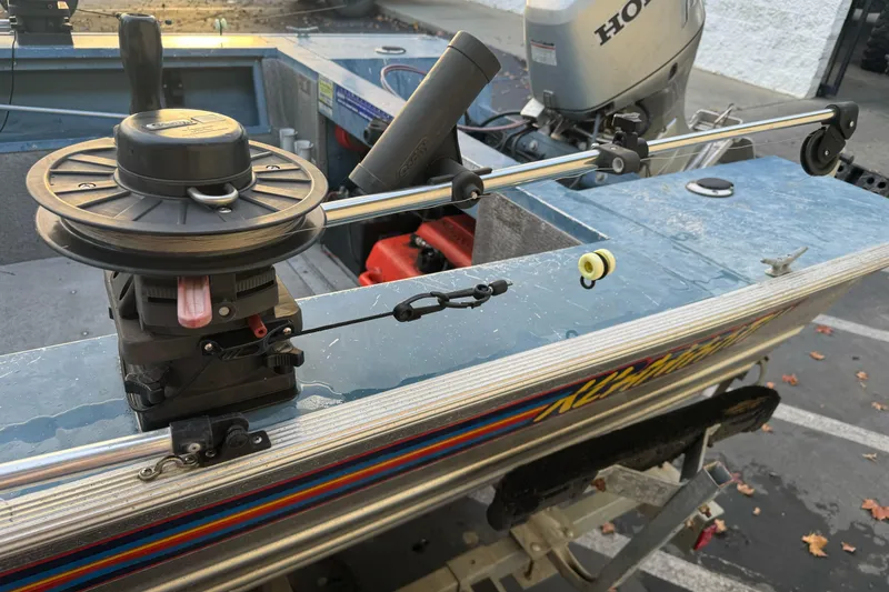 Slide: The Image of 1998 Klamath 18 Open boat with fishing equipment and Honda motor in a parking lot. - 12