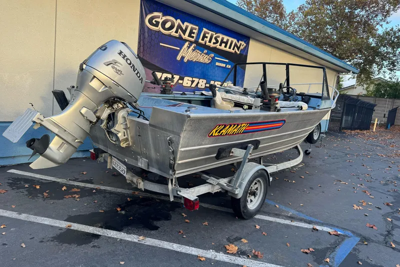 Slide: The Image of 1998 Klamath 18 Open boat with Honda motor on trailer, parked outside a fishing store. - 3