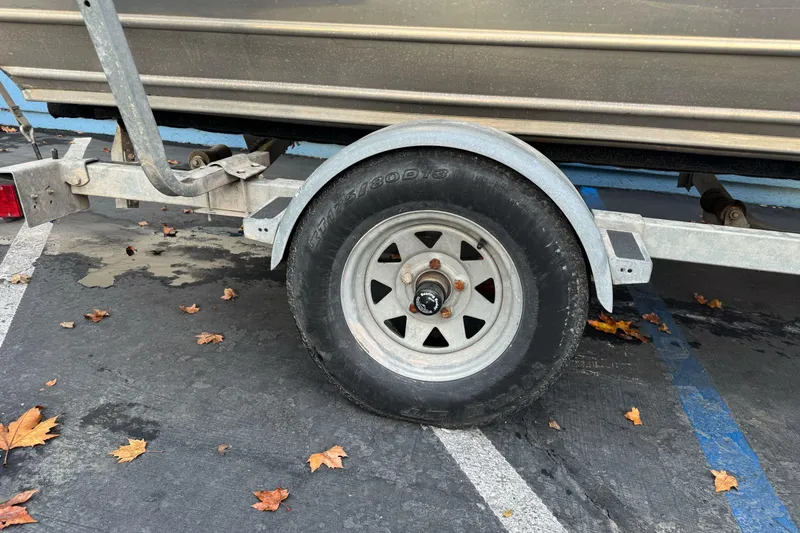 Slide: The Image of Trailer wheel of a 1998 Klamath 18 Open boat, parked on asphalt with autumn leaves. - 5