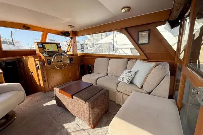 Slide: The Image of 1983 Egg Harbor 40 Sedan interior with helm, beige sofa, and nautical decor. - 11