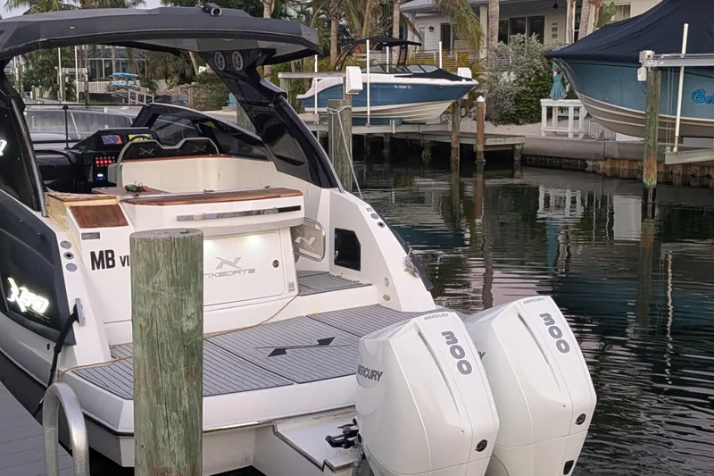 Slide: The Image of 2023 NX Boats 340 Sport Coupe docked with twin Mercury 300 engines. - 10