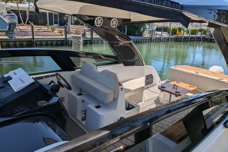 Slide: The Image of 2023 NX Boats 340 Sport Coupe interior with seating and table, docked by the water. - 101