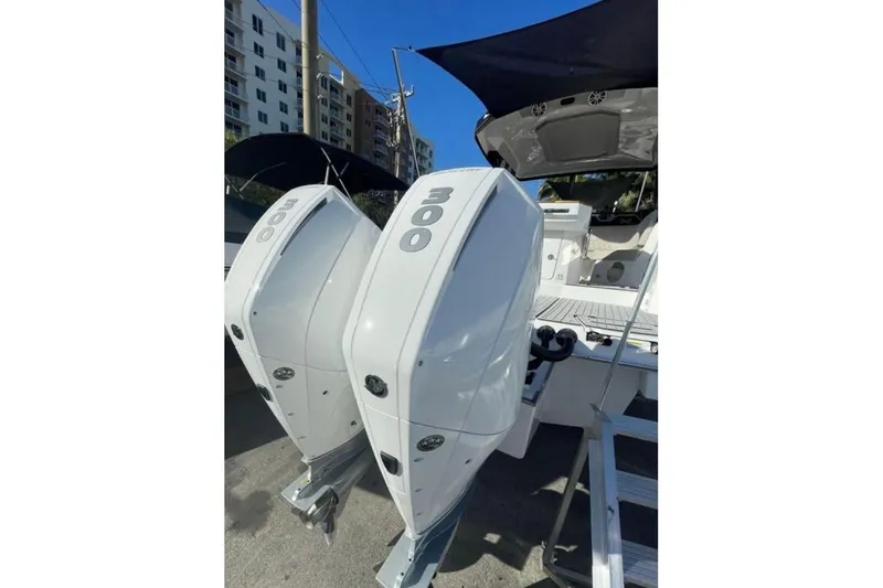 Slide: The Image of 2023 NX Boats 340 Sport Coupe with dual 300 horsepower engines, docked under clear skies. - 15