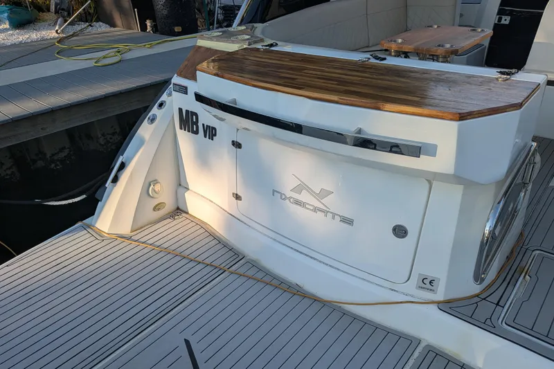 Slide: The Image of 2023 NX Boats 340 Sport Coupe deck with wooden countertop and seating area. - 18