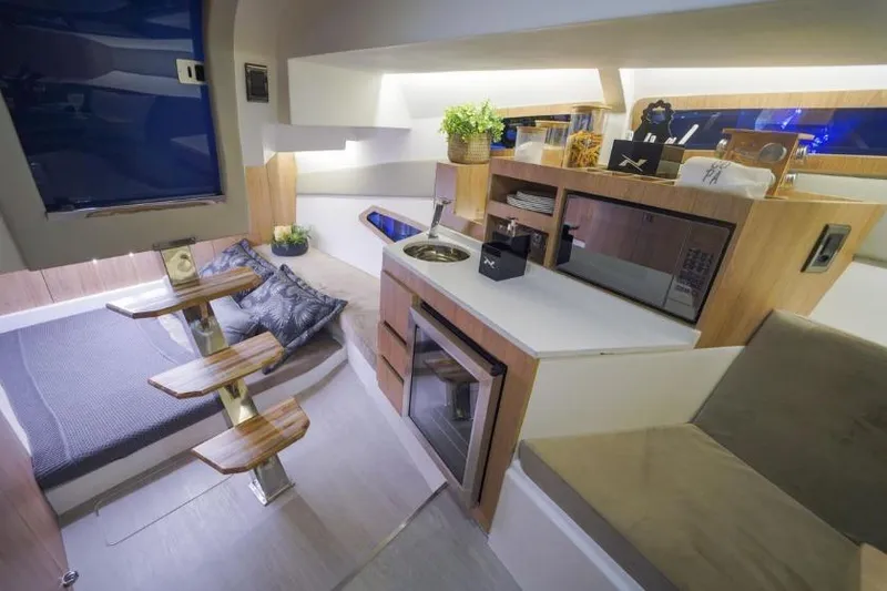 Slide: The Image of Interior of 2023 NX Boats 340 Sport Coupe, featuring modern kitchen and cozy sleeping area. - 2