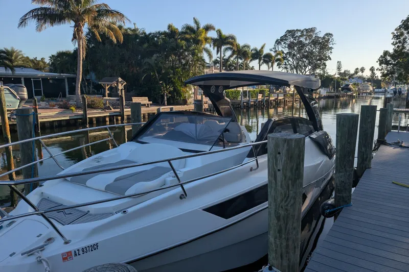 Slide: The Image of 2023 NX Boats 340 Sport Coupe docked by a scenic waterfront with palm trees. - 26