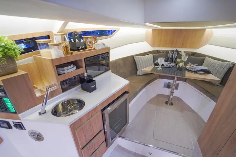 Slide: The Image of Interior of 2023 NX Boats 340 Sport Coupe, featuring a modern kitchen and cozy dining area. - 3