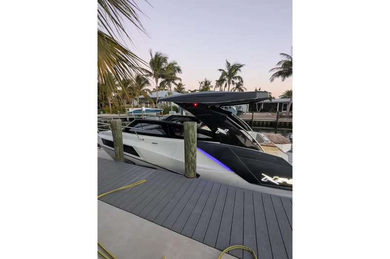 Slide: The Image of 2023 NX Boats 340 Sport Coupe docked near palm trees at sunset. - 31