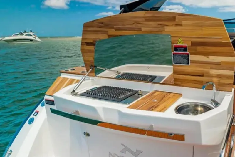 Slide: The Image of 2023 NX Boats 340 Sport Coupe with outdoor kitchen on a sunny day. - 34